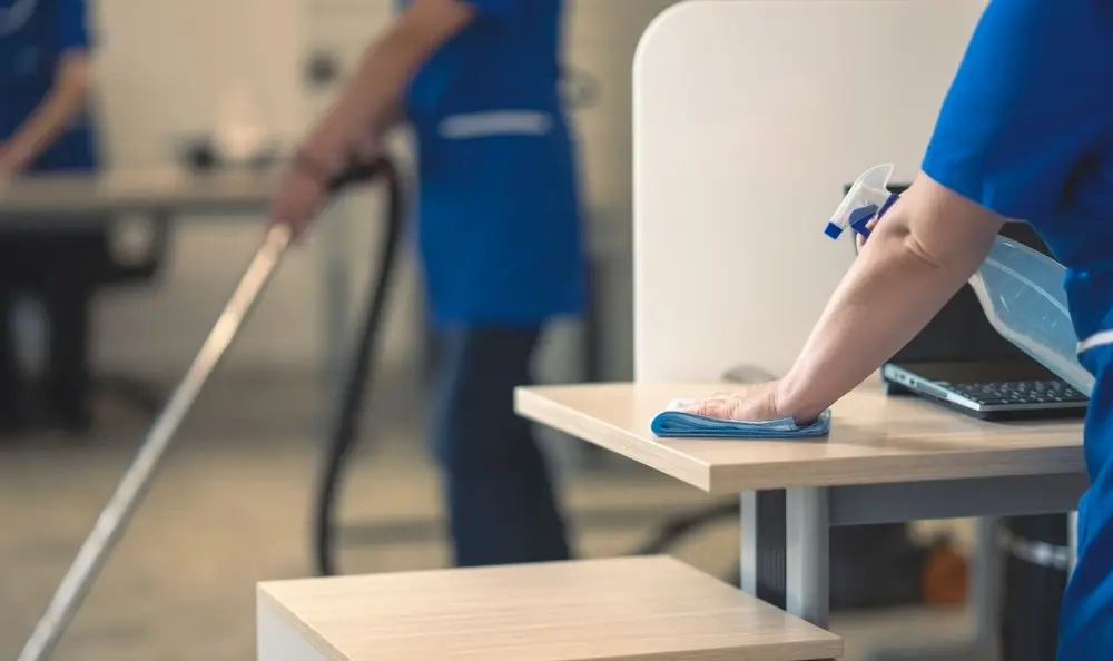 Cleaner wiping down a desk in an office