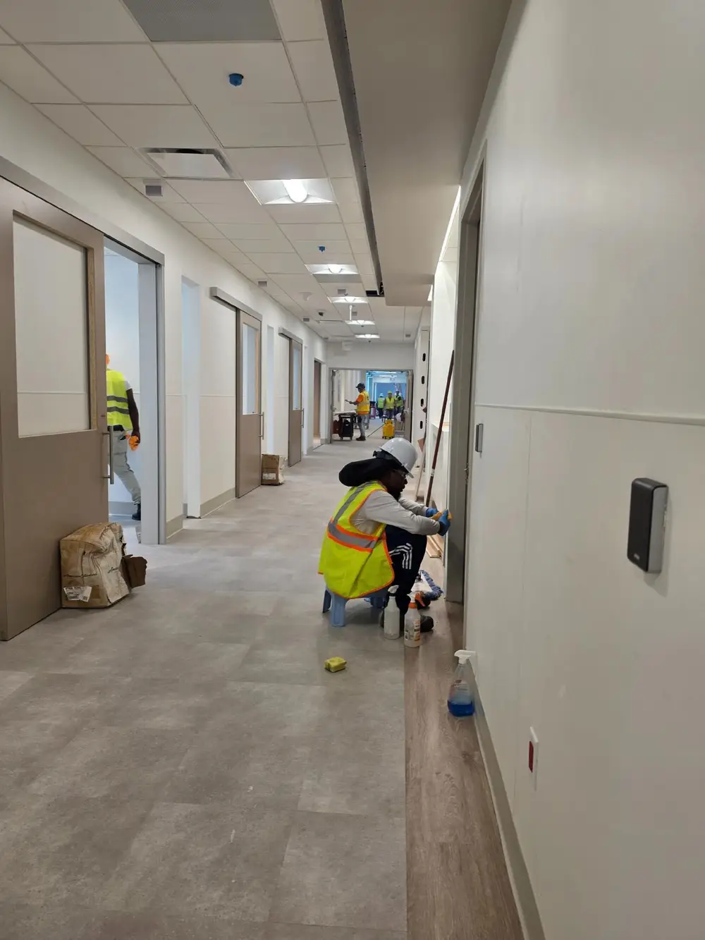 Crew in hard hats and safety vests cleaning a new corridor
