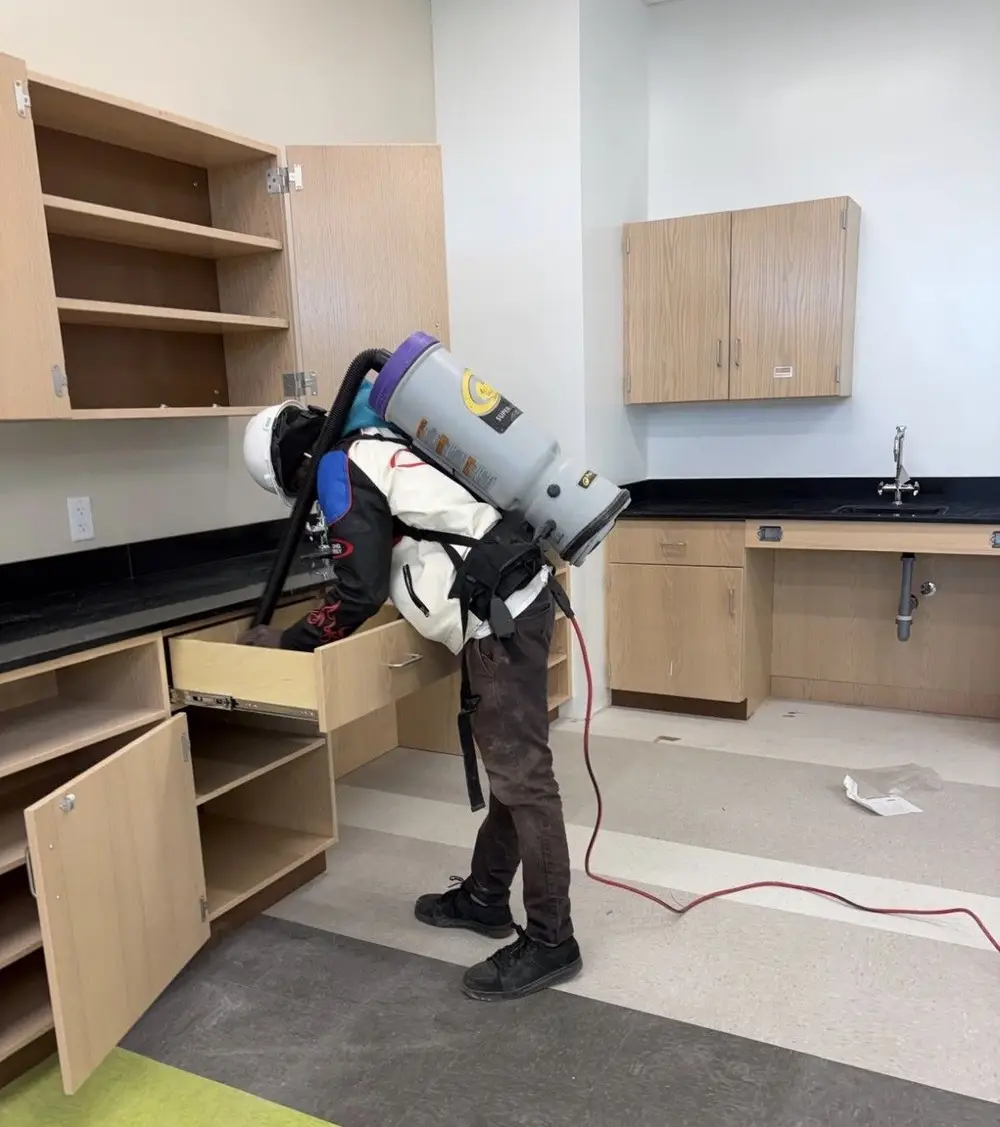 Legally Clean crew member vacuuming new cabinets during a school final clean